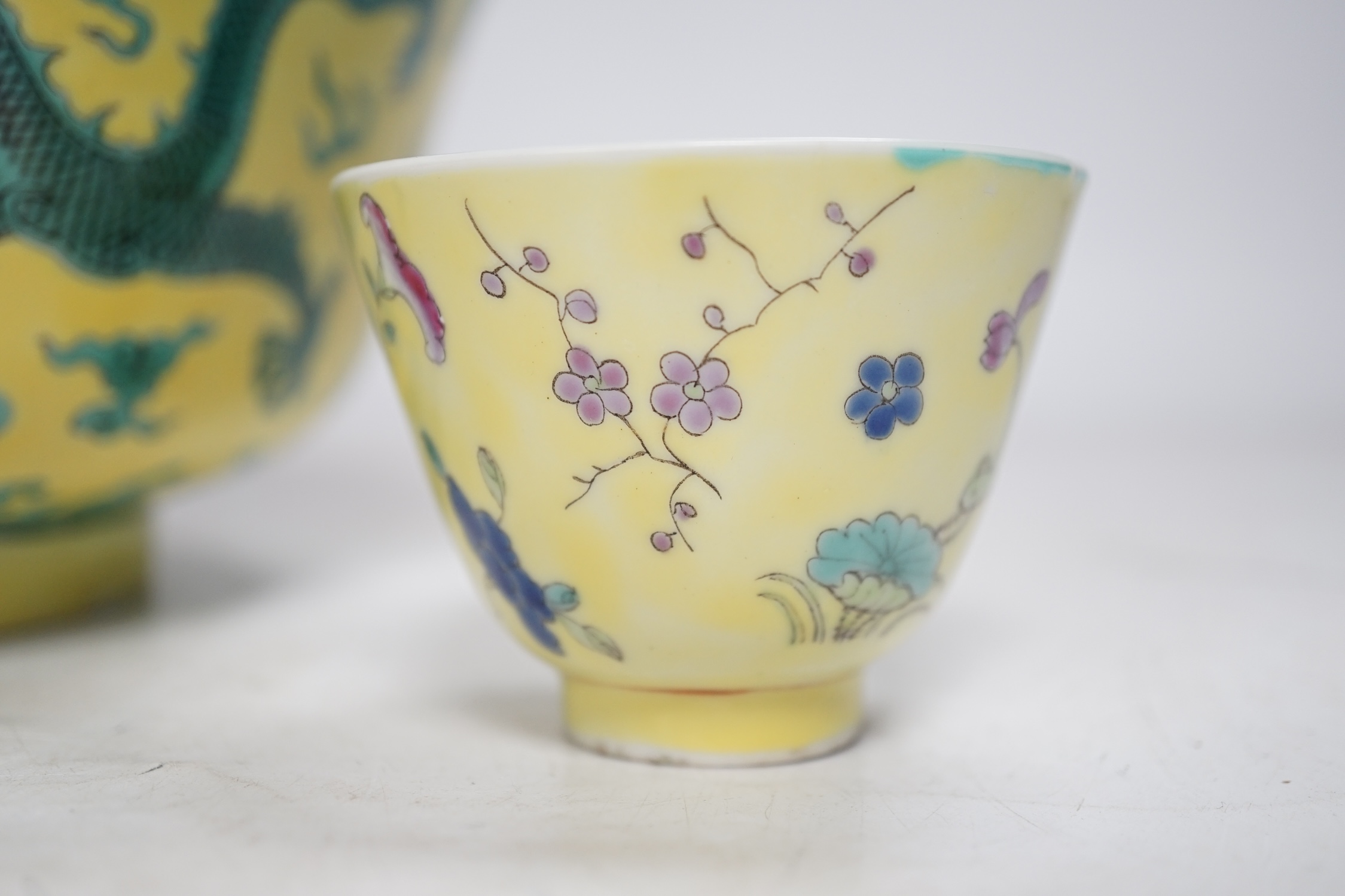 A Chinese yellow ground 'dragon' bowl, probably late Qing dynasty, and a similar floral cup, bowl 9cm high, 18.5cm diameter. Condition - bowl has a large section restored